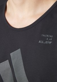 Maglietta sportiva nera con scollatura tonda, caratterizzata da accenti grafici grigi testurizzati e testo stampato "TRAINING A_49 ALL_GYM®."