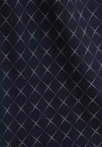 Granatowa tkanina z wzorem diamentu uformowanym z małych białych kropek, tworząca teksturowany, geometryczny wzór na materiale.