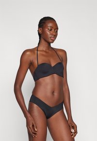 Bikini noir avec un haut à bonnets moulés sans bretelles et un bas en forme de V. Fabriqué à partir d'un tissu lisse avec des coutures minimales.