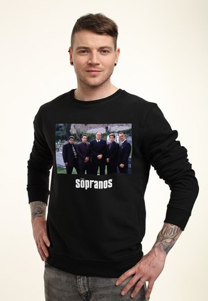 Černá mikina se šedým potiskem pěti postav v oblecích, pod nimiž je text "The Sopranos". Kulatý výstřih a žebrované manžety.
