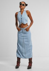 Világoskék farmer crop top és hosszú szoknya elöl gombokkal, piros mintás csizmával párosítva. Sima textúra, a ruhán nincsenek látható minták.