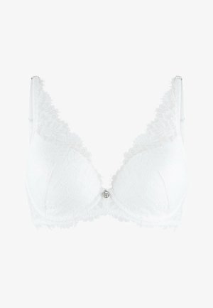 White lace bra featuring a deep V design, textured floral pattern, scalloped edges, and a central decorative hardware detail. Adjustable straps.
