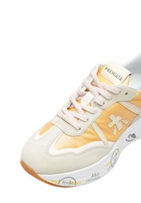 Baskets Premiata beige et orange avec lacets blancs, languette marquée, semelle texturée et logo cousu sur le côté.