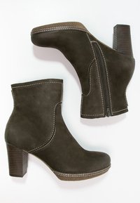 Botines de ante marrón con tacones de bloque, cremallera lateral y costuras en contraste blancas, exhibidos sobre un fondo blanco.