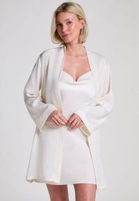 White silk kimono with wide sleeves, featuring a smooth texture and a loose fit, worn over a matching fitted slip dress.