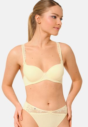 Soutien-gorge jaune clair avec des bordures en dentelle et des nœuds décoratifs sur les bretelles, avec des bonnets lisses et un slip assorti avec des détails en dentelle.