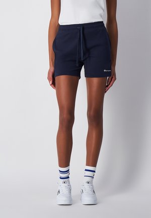 Pantalones cortos de algodón azul marino con cintura elástica y cordón, que presentan un pequeño logo blanco en la pierna. Textura suave.
