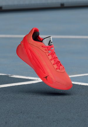 Raudonas sportinis batelis su zomšos ir tinklinio viršumi, raištelių užsegimu, paminkštu apykakle ir juodu logotipu šone. Lengvas dizainas geresniam našumui.