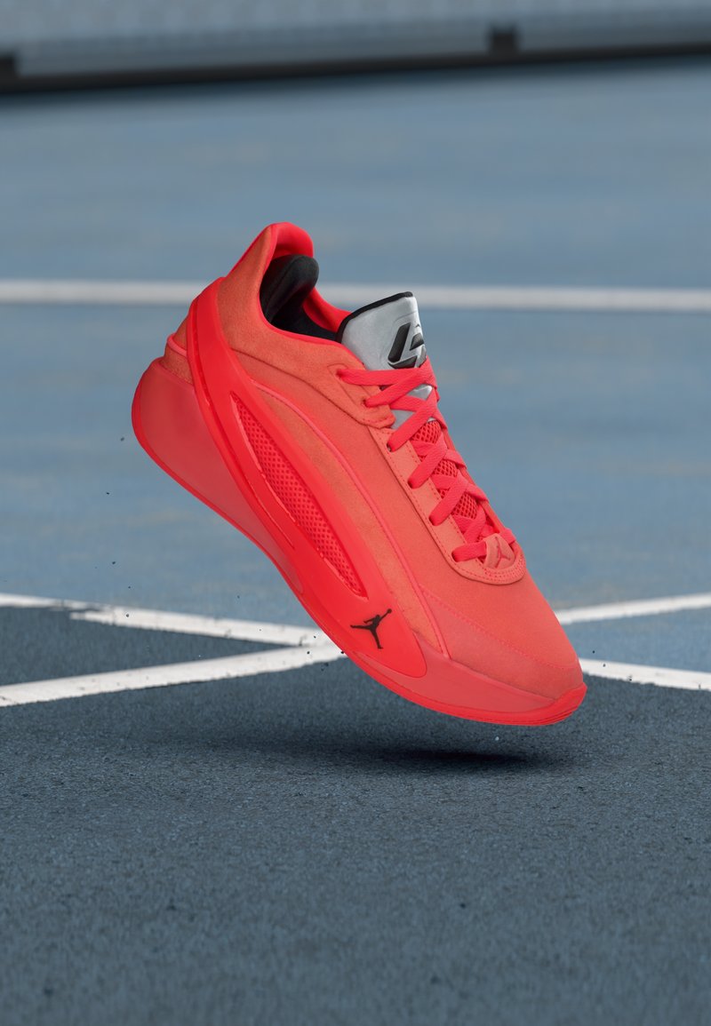 Κόκκινο αθλητικό παπούτσι με επάνω μέρος από σουέτ και δίχτυ, κλείσιμο με κορδόνια, επενδεδυμένο κολάρο και μαύρο λογότυπο στο πλευρό. Ελαφρύς σχεδιασμός για απόδοση.