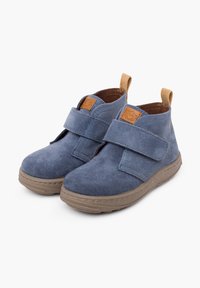 Stivaletti alla caviglia in suede blu con cinturino in Velcro, dettagli in suede beige e suole in gomma. Presentano una punta rotonda e un minimo dettaglio di cucitura.