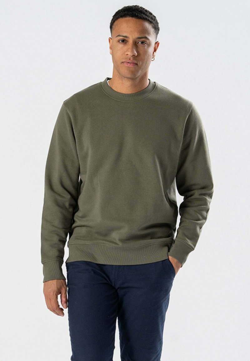 Olivenfarvet crewneck sweatshirt i blød stof med ribbede manchetter og kant, parret med marineblå bukser. Simpelt design uden mønstre.