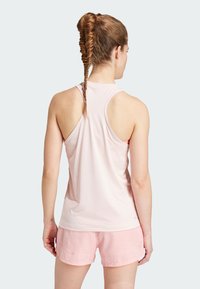 Light pink athletic tank top with racerback design, made of smooth fabric. Paired with light pink shorts, with subtle texture and trim.