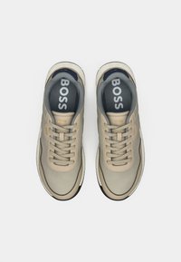 Baskets BOSS beiges et grises avec lacets vues du dessus sur un fond blanc, montrant des semelles intérieures et des logos sur les côtés.