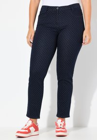 Námořnické modré džíny s bílými puntíky, středně slim fit, denimový materiál, standardní pět kapes, spárované s červenými a bílými teniskami.