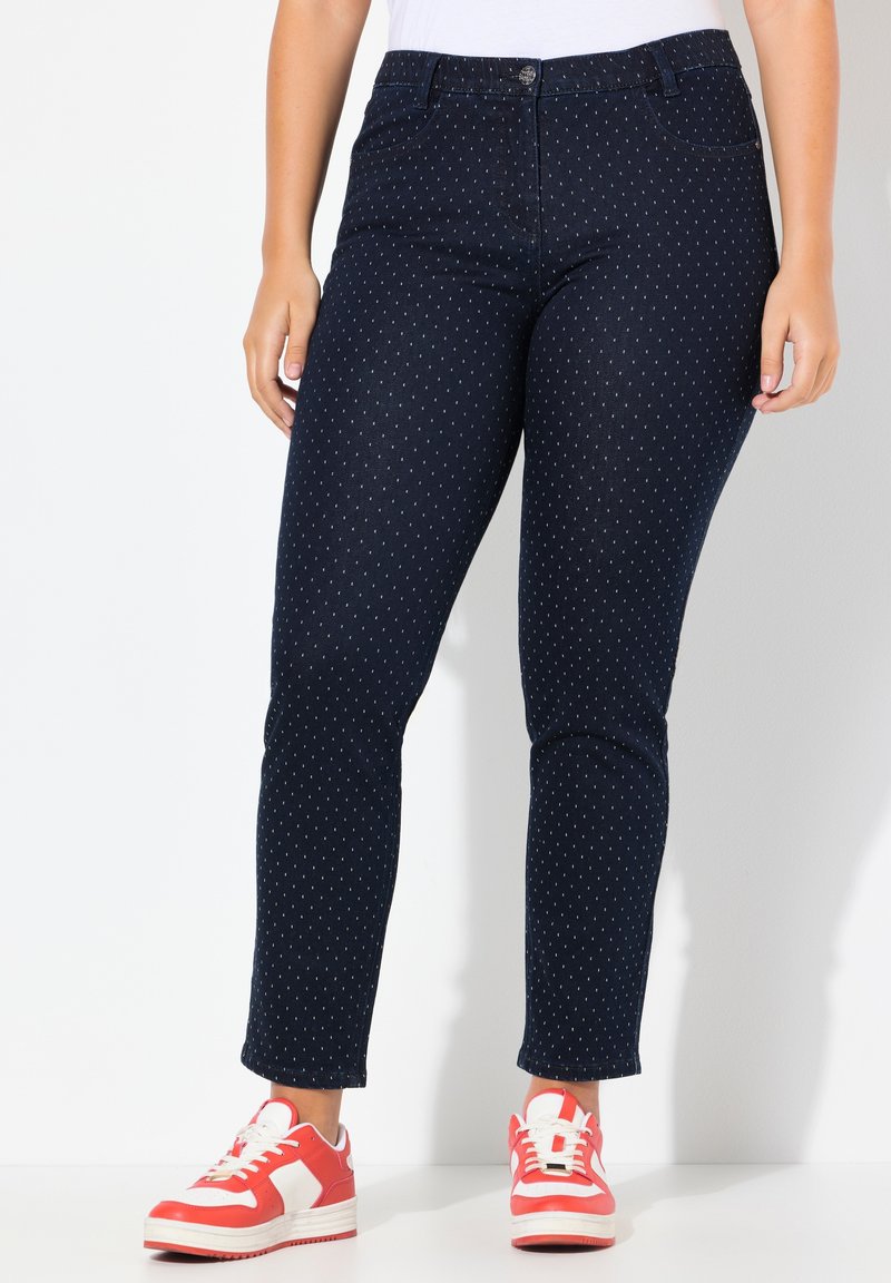 Námořnické modré džíny s bílými puntíky, středně slim fit, denimový materiál, standardní pět kapes, spárované s červenými a bílými teniskami.