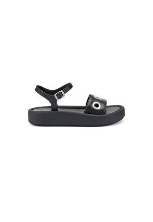 Sandal nera con suola piatta, cinturino alla caviglia regolabile e dettaglio decorativo a occhiello sul cinturino anteriore. Realizzata in materiale sintetico.