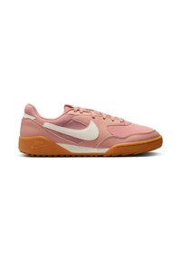 Baskets Nike de couleur rose pâle avec des accents blancs et une semelle en caoutchouc marron. Présentent une texture lisse et une forme arrondie, avec un design à lacets.