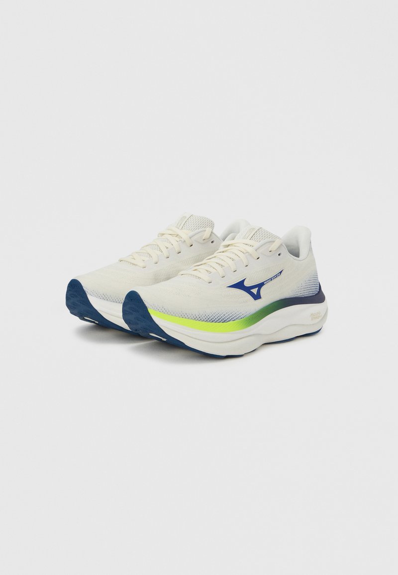 Zapatillas blancas para correr con parte superior de malla transpirable, detalles en azul y verde, puntera redondeada, suela acolchada y suela exterior con agarre texturizado.