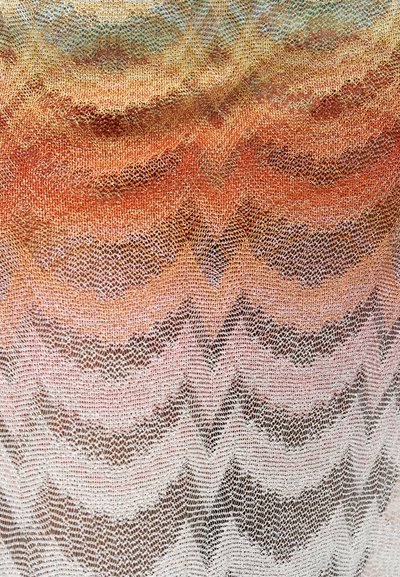 Ευαίσθητο πολύχρωμο δαντελένιο ύφασμα με περίπλοκα κυματιστά και ζικζακ μοτίβα σε ροζ, πορτοκαλί και χρυσούς τόνους, δημιουργώντας μια υφή με διαφανές εφέ.