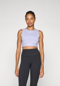 Lila sport crop top met een ronde halslijn en het Nike-logo, gecombineerd met hoge zwarte leggings. Glad, aansluitend materiaal.
