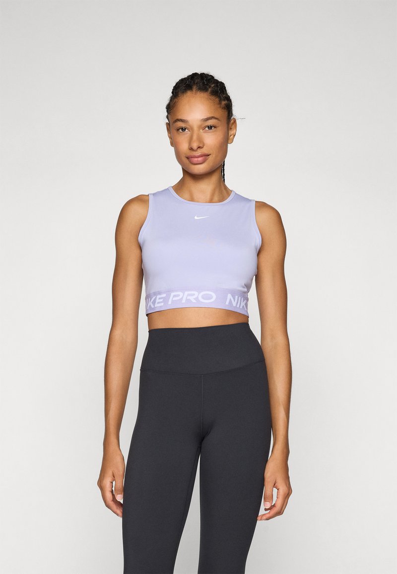 Lila sport crop top met een ronde halslijn en het Nike-logo, gecombineerd met hoge zwarte leggings. Glad, aansluitend materiaal.