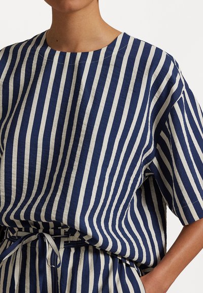 Navy and cream striped top made of lightweight fabric, featuring a round neckline and short sleeves. Includes a drawstring detail at the waist.
