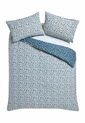 Doppelbett mit weißer und blauer klein geblümter Bettdecke und passenden Kissen, wobei die Ecke der Bettdecke umgefaltet ist, um das Rückseitenmuster zu zeigen.