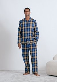 Blå och beige rutigt pyjamaset med en långärmad skjorta med knappar och matchande byxor, tillverkat av mjukt tyg med en avslappnad passform.