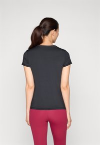 Black short-sleeve athletic top with a round neckline. The fabric is smooth and fitted, paired with pink leggings for a contrasting look.