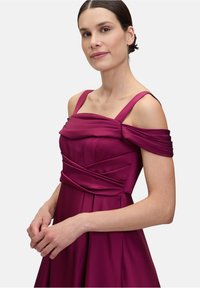 Fuksjowa sukienka wieczorowa z designem bez ramiączek, plisowanym korpusem, regulowanymi ramiączkami i zwiewną spódnicą. Gładka tekstura tkaniny.