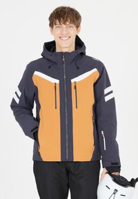 Herremodel vandtæt jakke med marineblå og orange paneler, hvide accenter, hætte og flere lynlåslommer. Letvægts og moderne design.