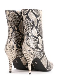 Návratové boty na vysokém podpatku v texturovaném, černobílém hadím vzoru, s špičatou špičkou a zužujícím se podpatkem, s elegantní siluetou.