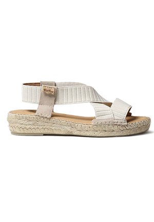 Raidallinen espadrillosandaali vaaleassa beessissä, jossa on kudottu juteepohja, säädettävät elastiset hihnat ja pehmeä pohja. Sandaalissa on hillitty logotyyli.