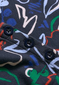 Marineblauer Stoff mit abstrakten Mustern in Blau, Grün, Rot und Creme. Verfügt über vier dunkle Knöpfe in einer Linie mit einer strukturierten Oberfläche.