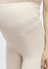 Μπεζ εγκυμονούσες κολάν με ριπ υφή, ψηλή μέση, εύκαμπτο ύφασμα και ελάχιστες ραφές, σχεδιασμένα για άνεση και εφαρμογή κατά τη διάρκεια της εγκυμοσύνης.