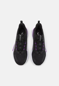 Chaussures de sport noires avec une tige en maille texturée, présentant des accents violets, une semelle flexible et un design à lacets.