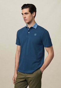 Námornícka polo tričko s golierom v denimsytle a krátkymi rukávmi; obsahuje malé logo na hrudi; hladký bavlnený materiál.