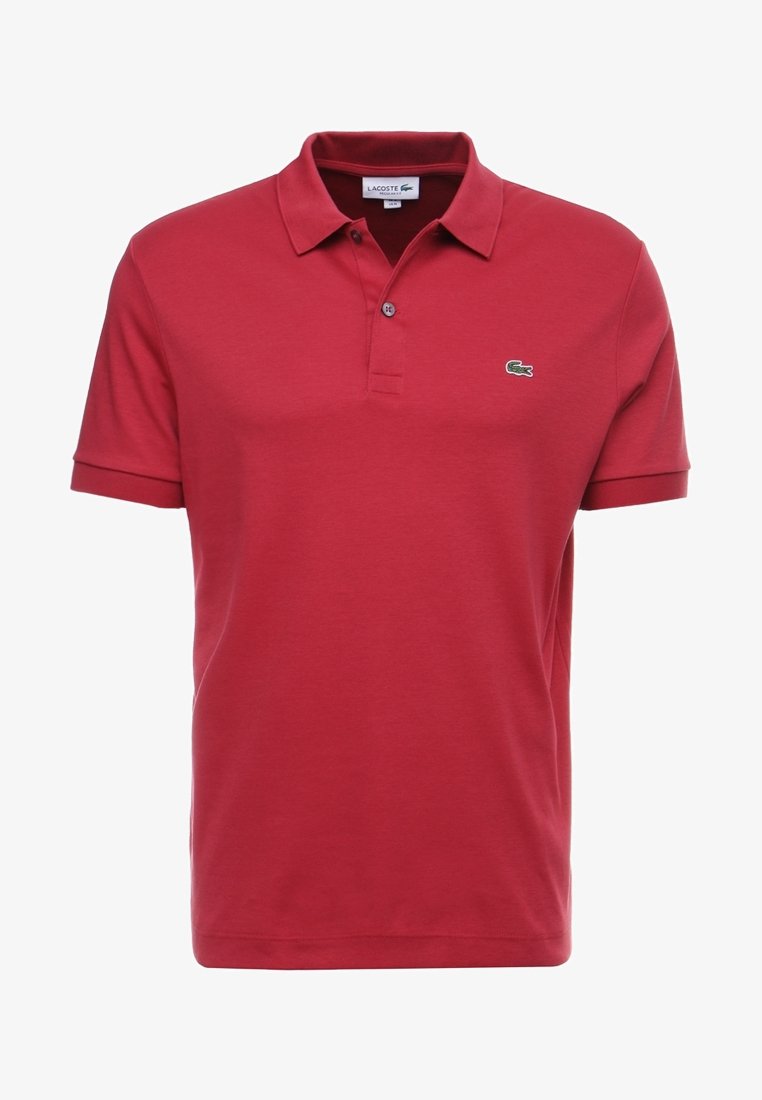 Rood katoenen poloshirt met korte mouwen, twee knopen aan de sluiting en een klein groen Lacoste-logo op de linkerborst. Soepele textuur.