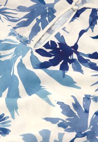 Weißer Stoff mit einem floralen Muster in verschiedenen Blautönen, mit hellblauen und dunkelblauen Blättern; weiche Textur; glatte Oberfläche.