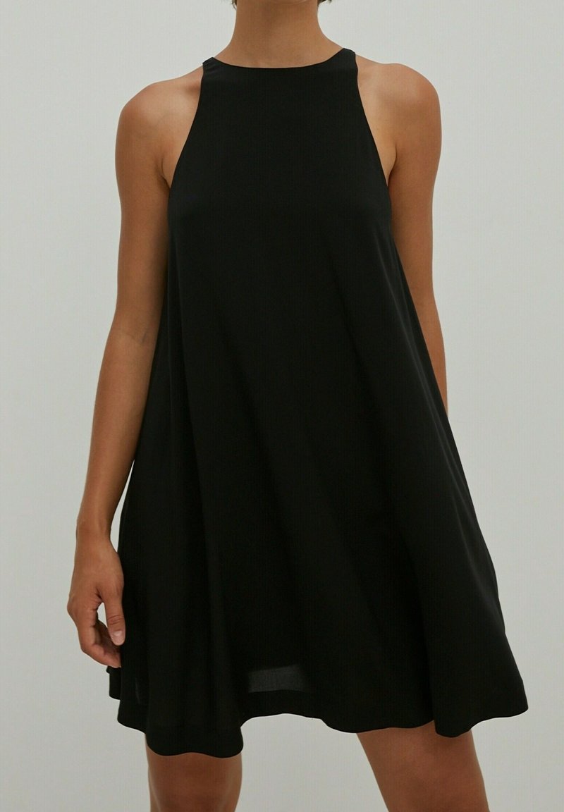 Vestido negro sin mangas con un escote alto, corte holgado y material fluido. Diseño simple sin patrones ni adornos prominentes.