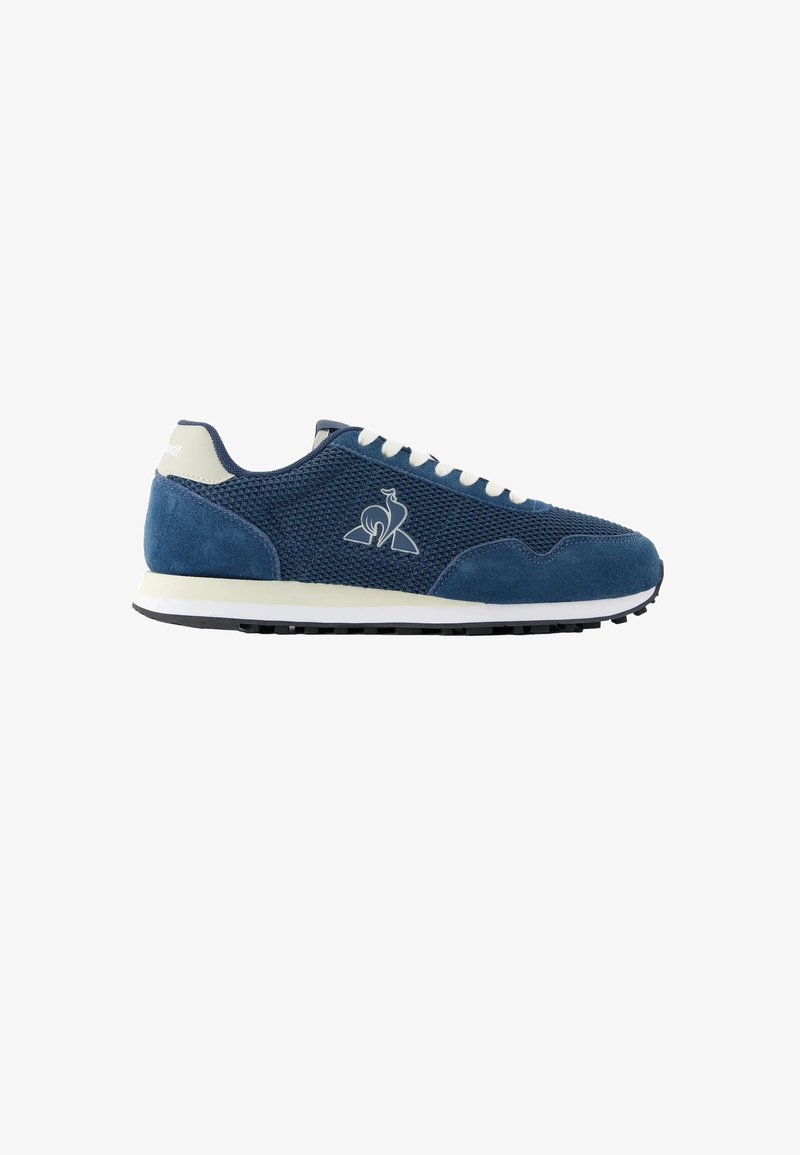 Blå og hvide lave sneakers med mesh- og ruskindspaneler, hvide snørebånd, gummisål og en stiliseret dyrelogo på siden.