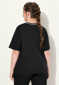 Zwarte korte mouwen t-shirt met witte stippen en een contrasterende kraag. Gemaakt van zachte stof, met een ontspannen pasvorm en een gladde textuur.