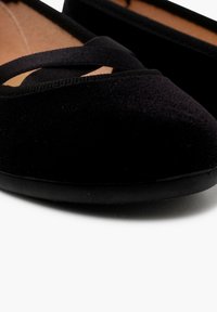 Černé semišové baleríny s kulatou špičkou, s texturovaným svrškem a dvěma křížovými pásky přes nárt.
