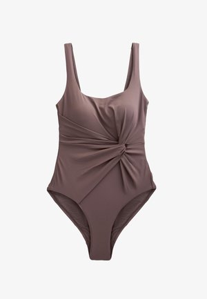 Gros plan sur un vêtement brun foncé avec un détail de nœud torsadé créant des plis de tissu froncés au niveau de la taille.