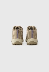 Chaussures de randonnée beiges avec un dessus texturé et un accent violet, dotées d'une semelle en caoutchouc robuste, conçues pour la stabilité et le soutien.