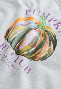 Illustrazione di una zucca a strisce colorate con testo viola "Pumpkin Art Club" e caratteri giapponesi su uno sfondo di tessuto grigio chiaro.