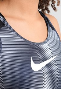 Débardeur de sport à motif noir et blanc avec un col rond et le logo Nike en blanc. Confectionné dans un tissu lisse et extensible.