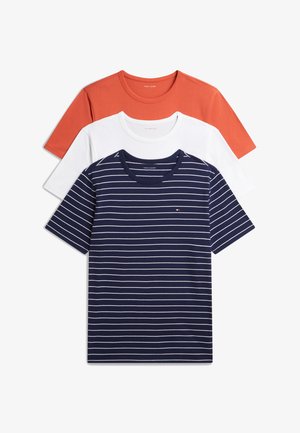 Uomo in piedi a piedi nudi che indossa una maglietta a maniche corte a righe blu navy e pantaloni blu scuro con coulisse su sfondo bianco.