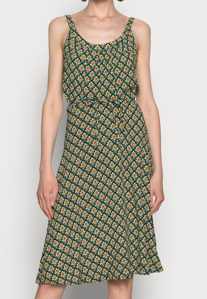 Grön blommig klänning med tunna axelband, figursydd vid midjan, med ett upprepande mönster i orange och gult, lätt tyg och svängig nederdel.
