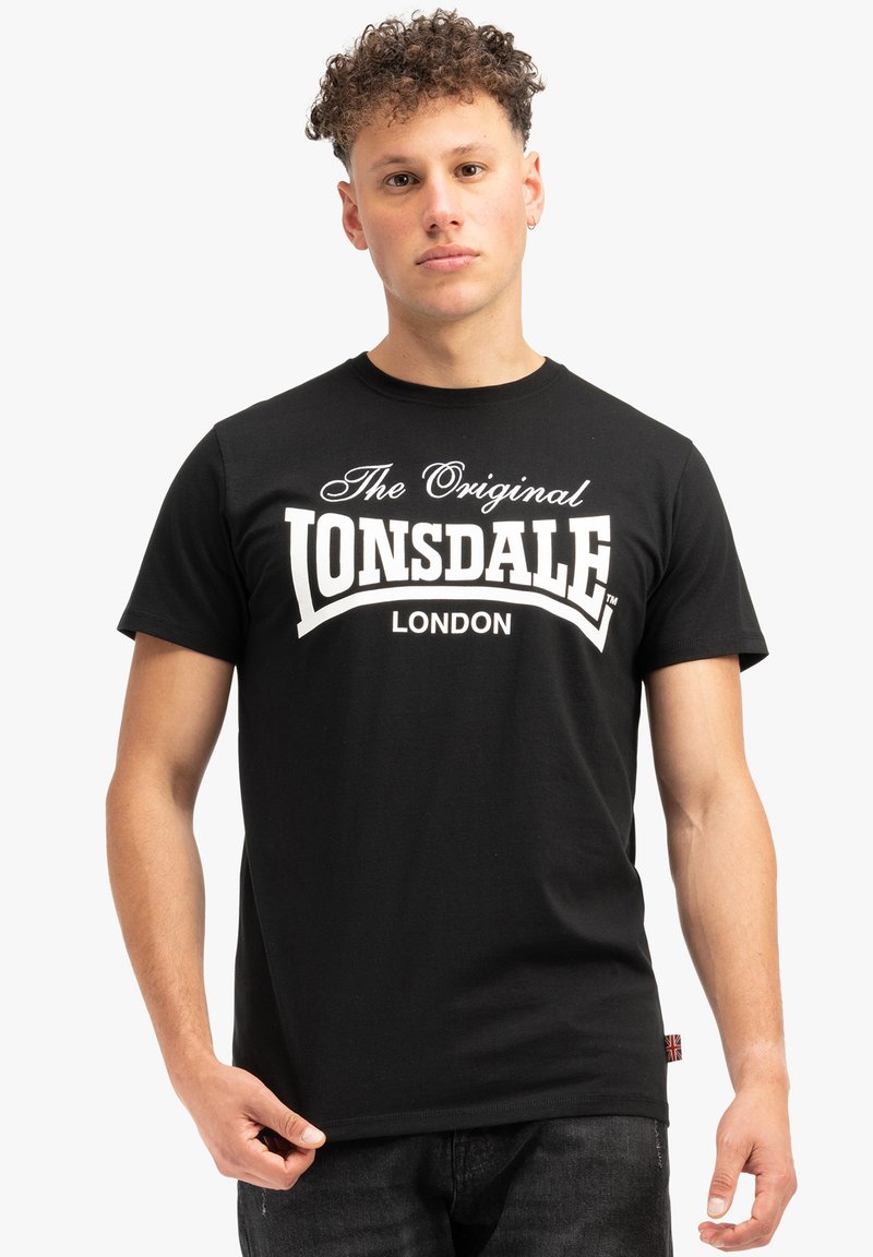 Crna pamučna majica kratkih rukava s natpisom "The Original Lonsdale London" bijele boje na prsima. Jednostavan, klasičan dizajn.